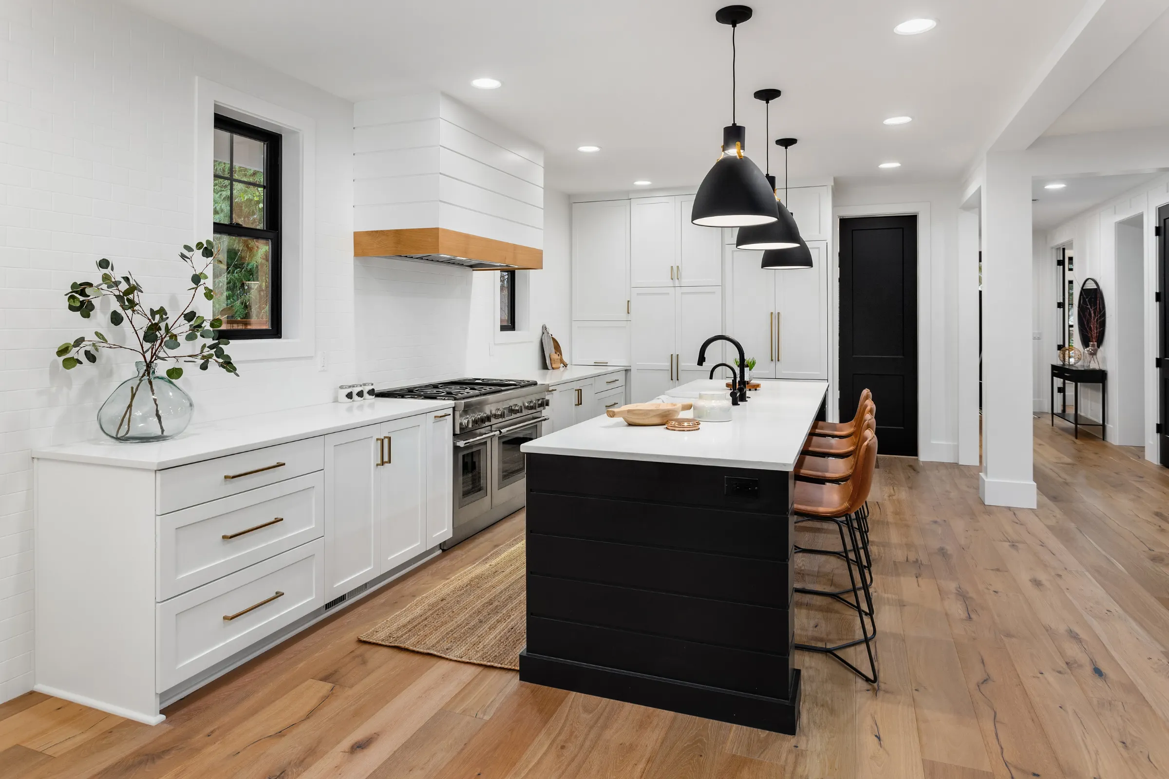 Kitchen remodeling in Los Angeles with modern white cabinets, black island, pendant lighting, and open layout